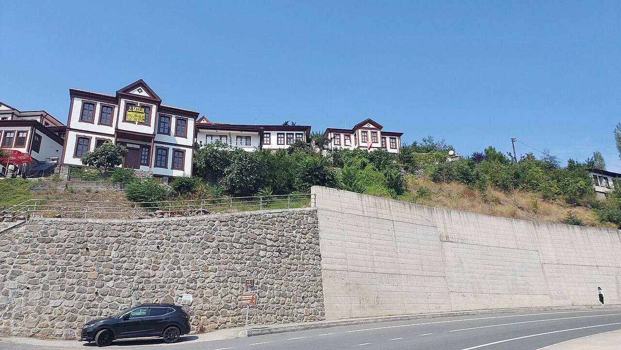Historic Ortamahalle houses on the hillside above a road in Akçaabat, 2025